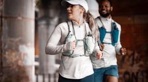 Two runners jogging under a bridge